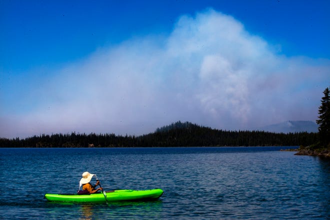 Bertha Gonzalez paddles her kayak on Waldo Lake at Shadow Bay as the Cedar Creek Fire burns on the other side of the lake on Tuesday. Three generations of her family have been camping at the popular destination.
