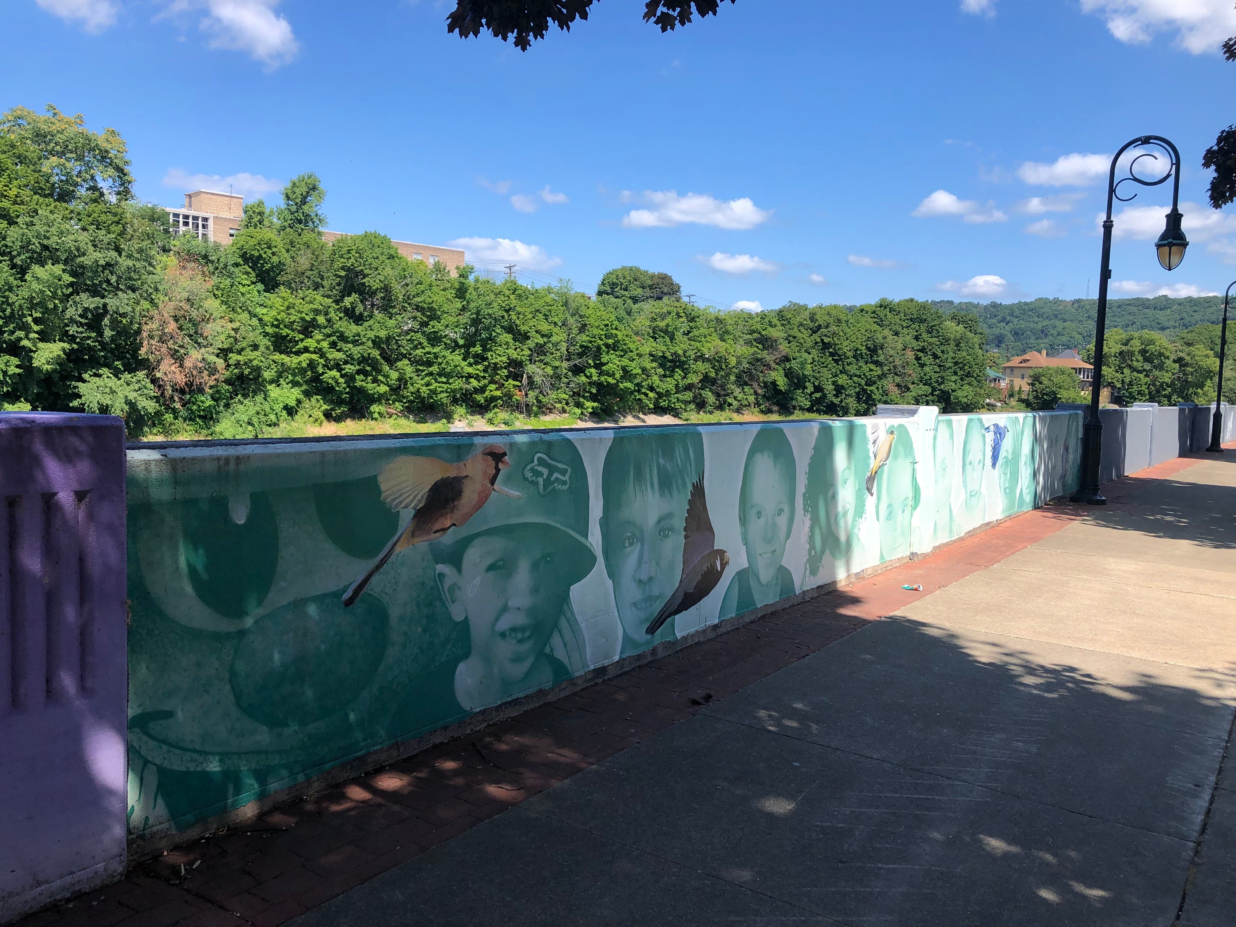 Children's faces and birds line part of the floodwall along the Chenango River in downtown Binghamton.