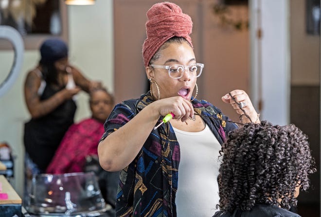 Tahli McLendon, 31, puts her finishes touches after braiding Sharell Franklin's hair at Thee Essenze Hair Salon and Barbershop near New Castle, Del.., on Tuesday, Aug. 16, 2022. McLendon braids hair for a living, an expression and profession rooted in personal, regional and cultural history, and she brings her art to Salisbury's National Folk Festival taking place from Aug. 26-28.