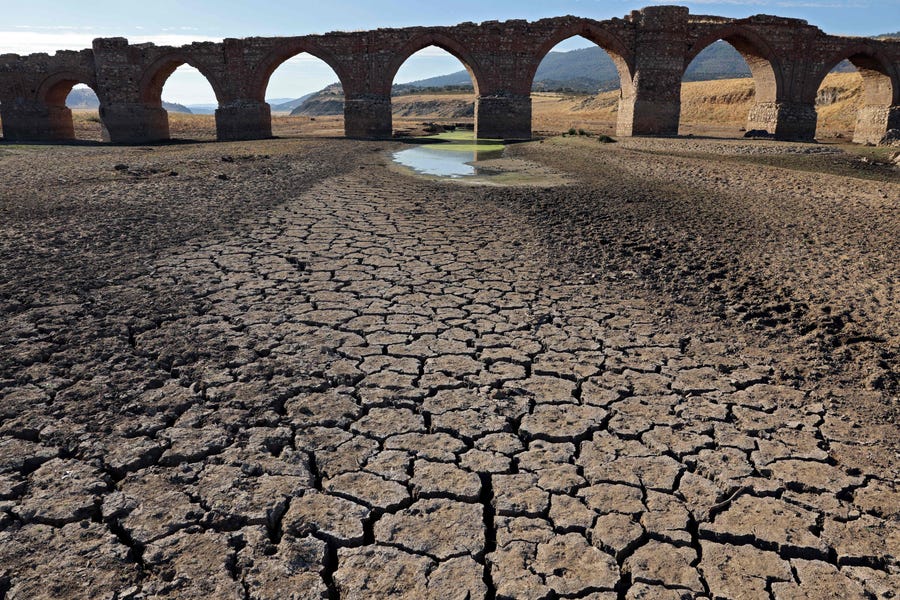 Part of the Guadiana river has dried up and gives way to dry land under the Puente de la Mesta medieval bridge in Villarta de los Montes, in the central-western Spanish region of Extremadura, on August 16, 2022. Temperatures in Spain have been very high this summer with several unusual heat waves. Scientists say human-induced climate change is making extreme weather events including heatwaves and droughts more frequent and more intense. 