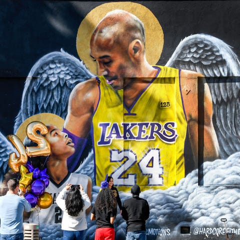 Fans gather at a mural of Kobe Bryant and his daug