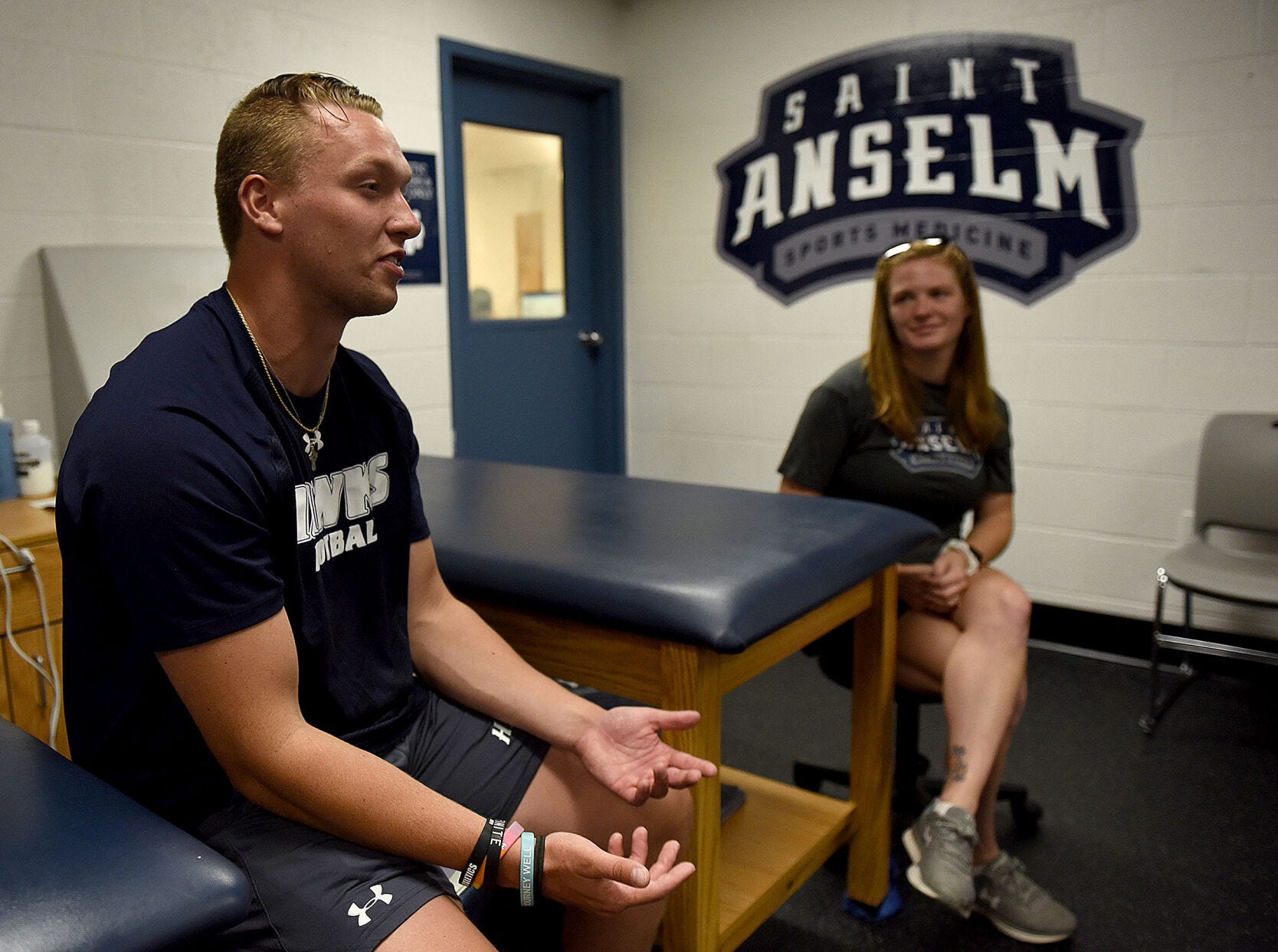 Football player Cillian Davis and Director of Sports Medicine and Athletic Performance Alyssa DeCotis speak with a reporter in the training room at St. Anselm College on Aug. 2, 2022.