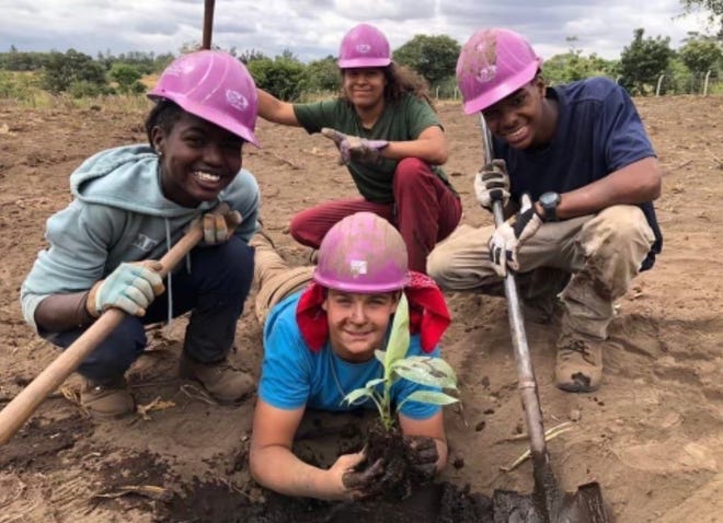 Bailey Earle, in the back, and team members planting trees in Tanzania. The group was part of a mission trip that did construction projects and tree planting.