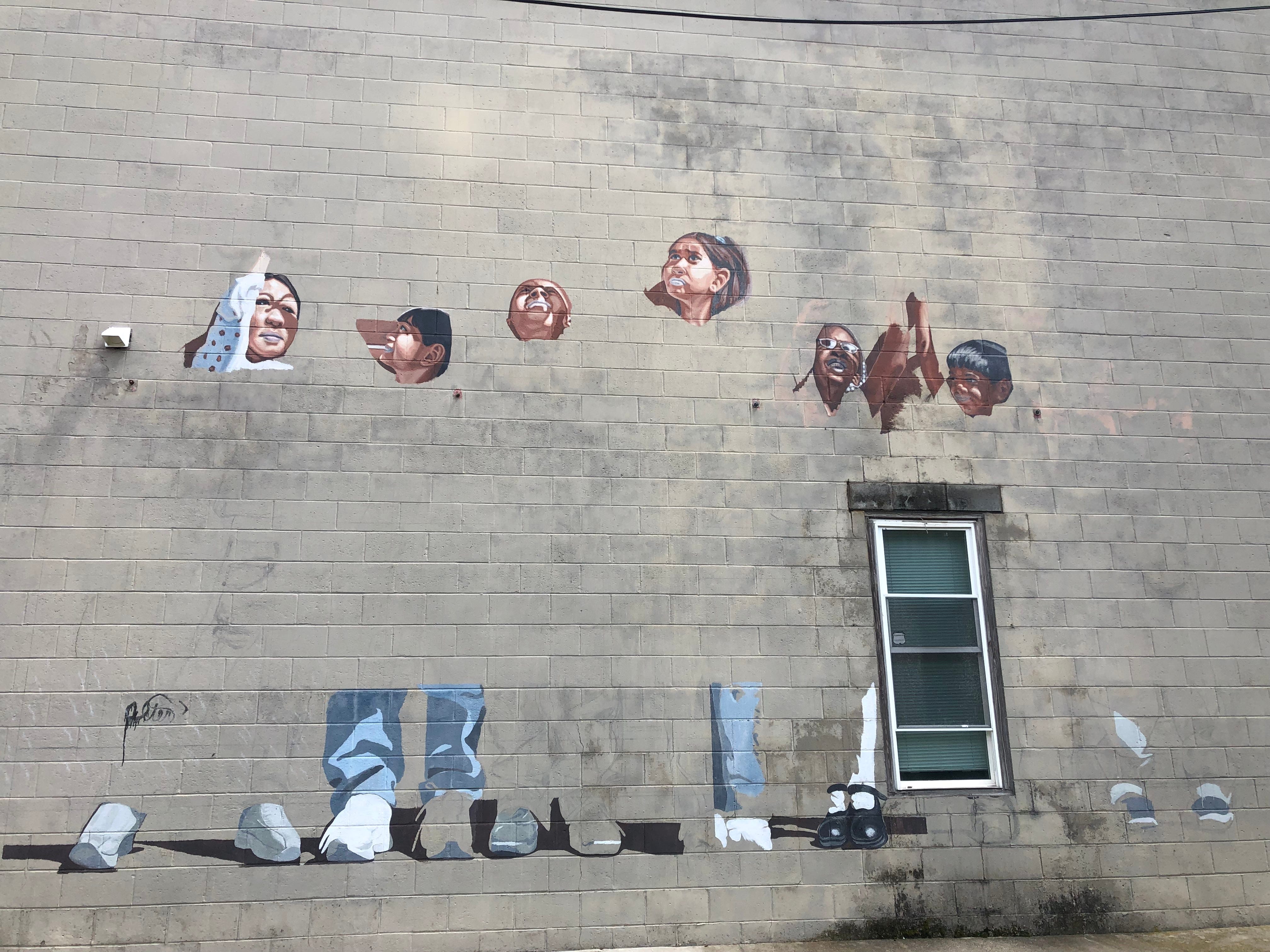 A group of six painted children stand, unfinished, on the side of 34 Lisle Ave. in Binghamton.