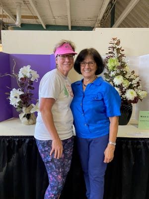 June Gebhardt, left, and Mary Lee Minor entered the first flower show at the Ohio State Fair. Behind them are very different entries for a class with all white flowers and dark foliage titled "Moonlight Garden."