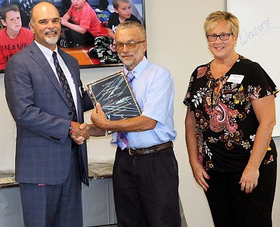 Coshocton City Schools Superintendent David Hire and board of education member Susan Mann receive a plaque from Robert Doughty, governing board member of the Muskingum Valley Education Service Center, recognizing the district for being with the educational service center for 25 years.