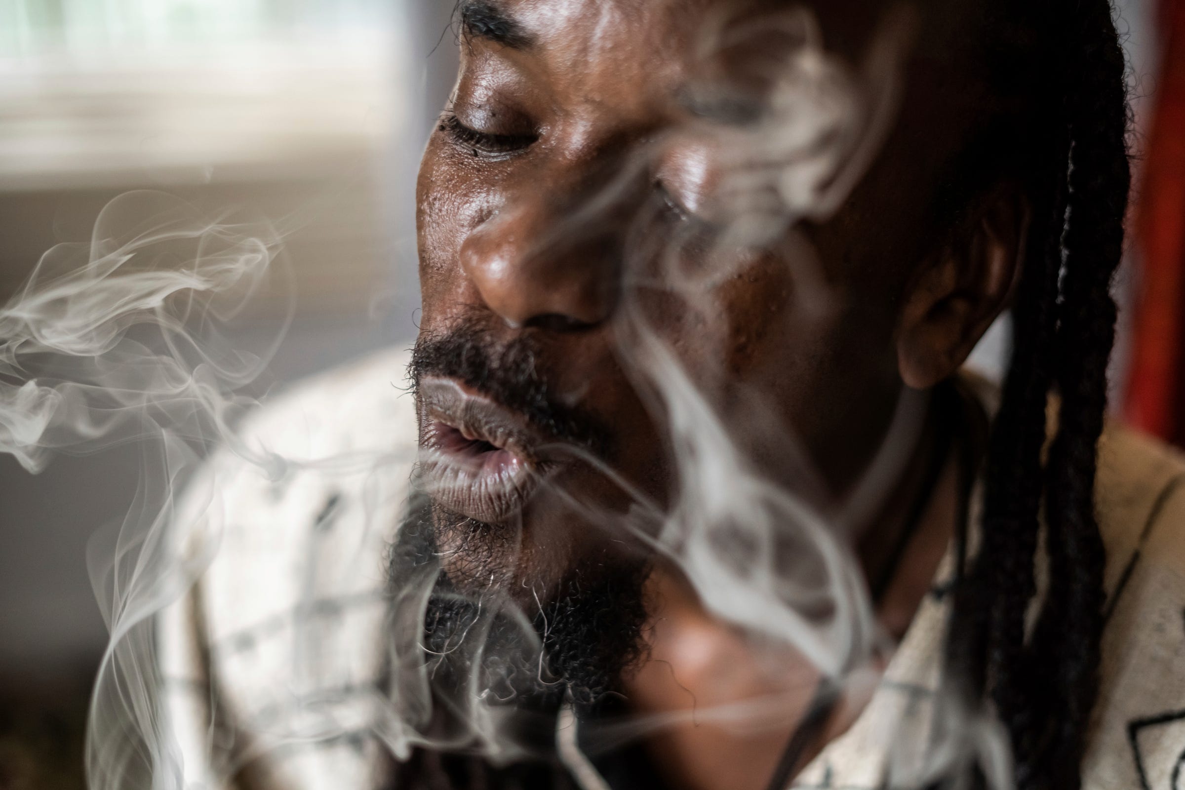 Psychonaut Academy of Detroit founder Sincere Seven, 43, blows smoke after taking a hit off a blunt at the Psychonaut Academy of Detroit, located in an old house on the city's west side, on Thursday, July 13, 2022.