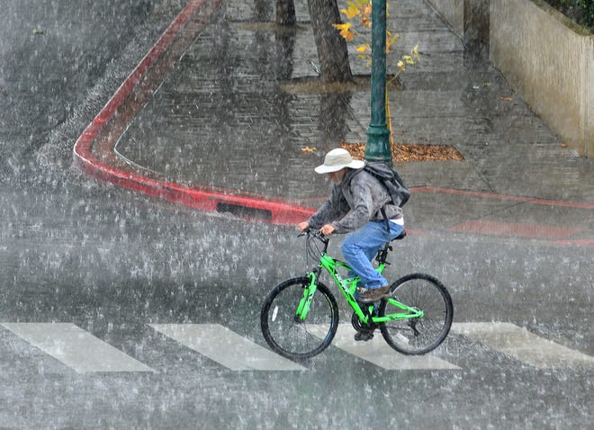A man crosses Sierra Street on his bike as the rain pours down in downtown Reno on August 18, 2022. 