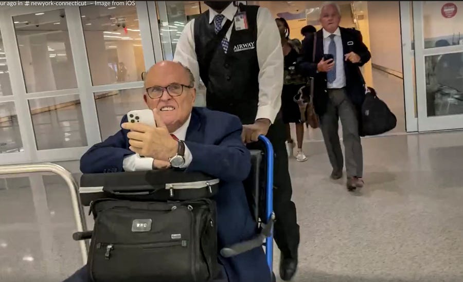 In this image taken from video, Rudy Giuliani is pushed in a wheel chair at New York's JFK airport after returning from Atlanta, where he faced hours of questioning before a special grand jury investigating attempts by former President Donald Trump and others to overturn his 2020 election defeat in Georgia, Wednesday Aug. 17, 2022.