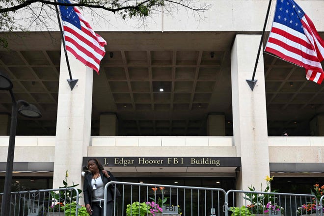A person walks between security fencing outside the Federal Bureau of Investigation headquarters in Washington, D.C. on August 15, 2022.