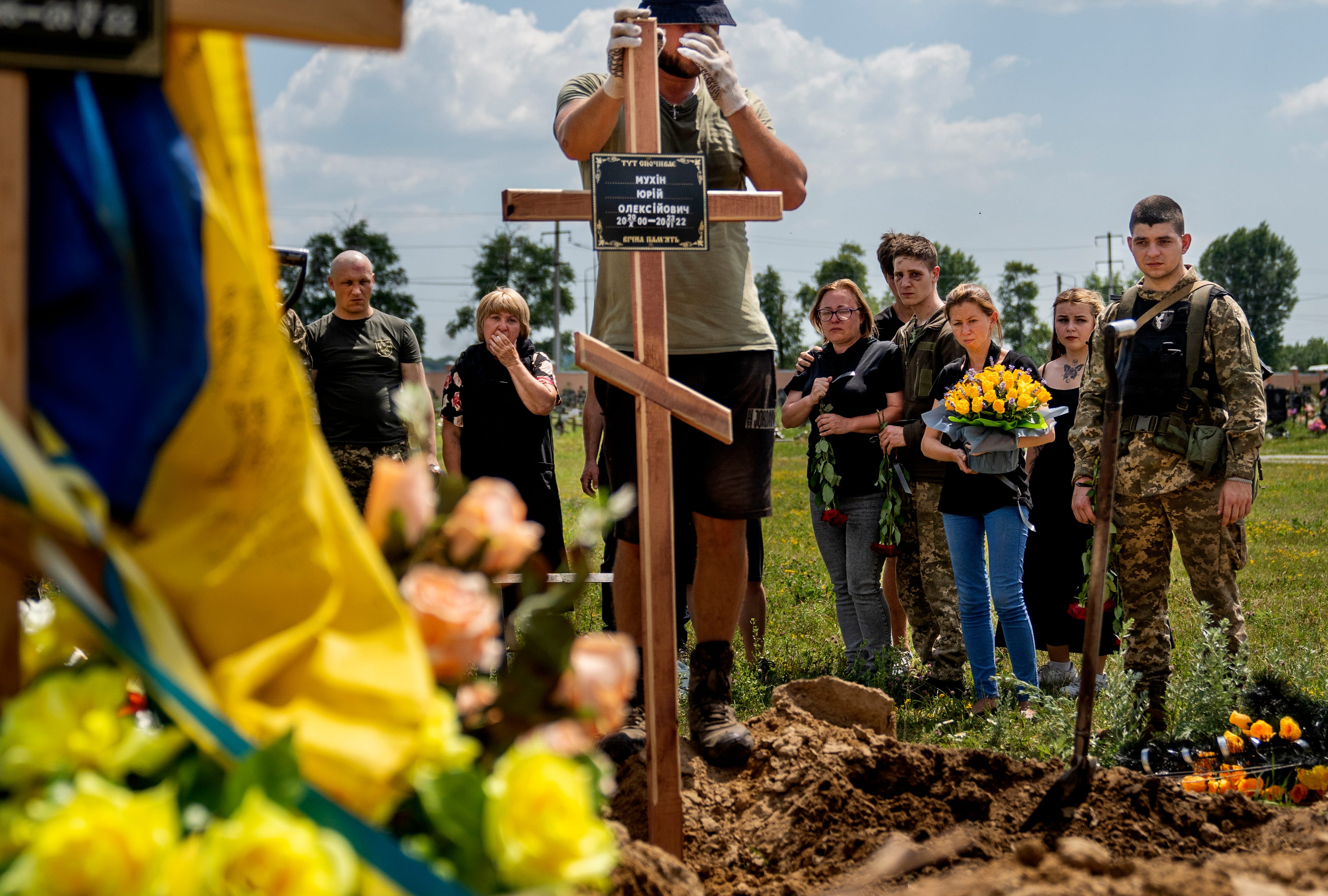 Family and friends watch as a cross is placed to mark the grave of fallen Ukrainian solider Yuriy Mukhin at Kharkiv Cemetery number 18, June 28, 2022.