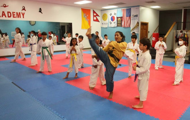 Kaushila Khanal Karmacharya, the owner of Sunshine Taekwondo Academy in Akron, demonstrates a kick to her students as she leads a class.