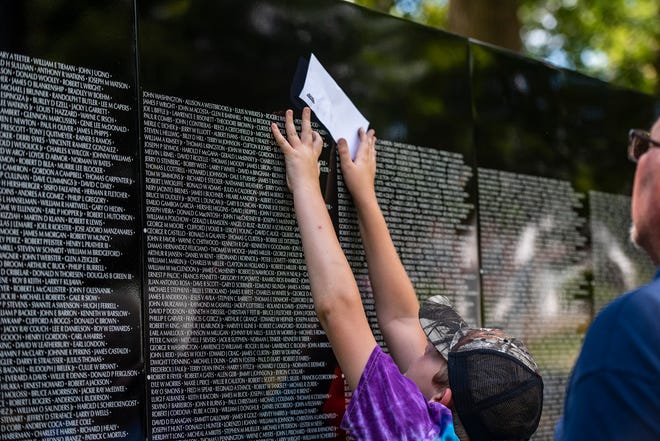 Grant Veasey 12, of Butler, can't quite reach the name of his grandfather's cousin, Lester J. Veasey, on the Moving Wall in Ewing Park.