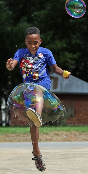 Seven-year-old Golden McKinney kicks and breaks a big bubble during the annual Kings Mountain Beach Blast Saturday afternoon, August 20, 2022, at Patriots Park.
