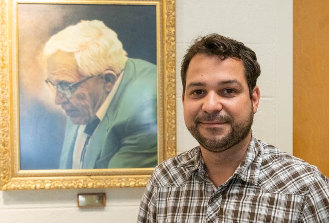 Wladimir Lyra in front of a portrait of Clyde Tombaugh in the Astronomy building. Lyra received a NASA-Emerging Worlds grant to further the understanding of how planetesimals form in circumstellar disks. Lyra says his research may have implications for the formation of Pluto.
