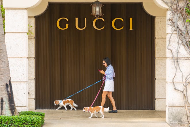 A woman walks her two dogs past the Gucci store on Worth Avenue in April 2020.