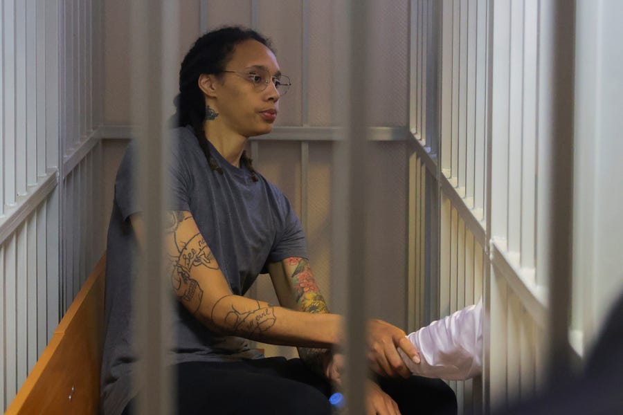 WNBA star Brittney Griner shakes hands with her laywer as she listens a verdict in a Russian courtroom.