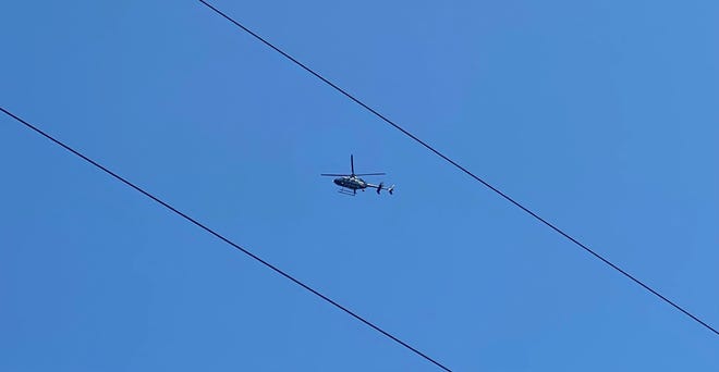 An Indiana State Police helicopter flies overhead during the search for a suspect in a fatal shooting the afternoon of Tuesday, Aug. 23, 2022, northeastern Delaware County.