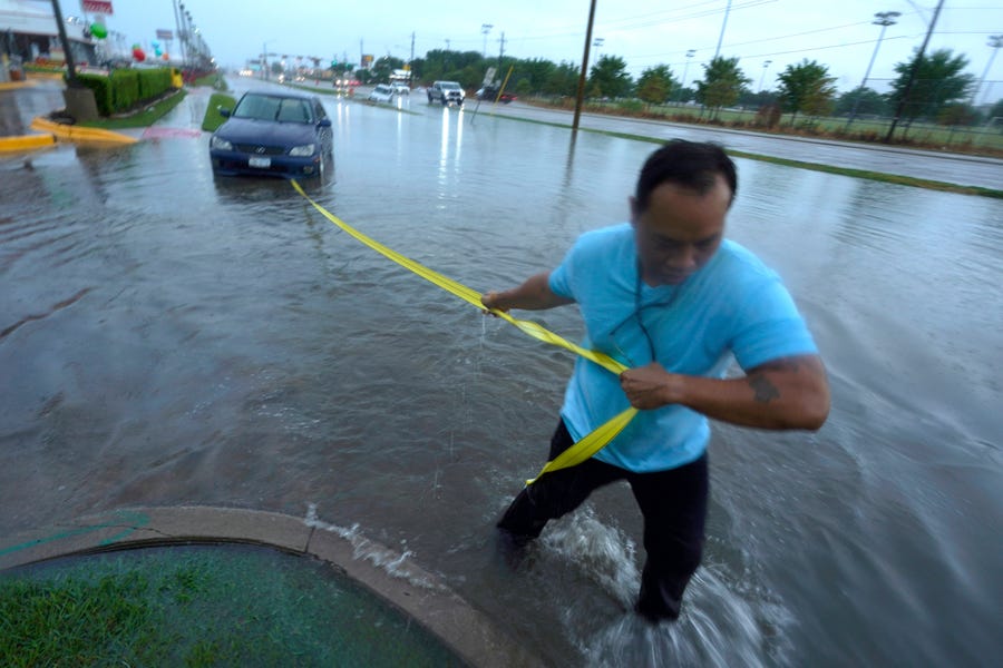 Mon Lun pulls a strap to his water stalled car before towing it out of receding flood waters in Dallas.