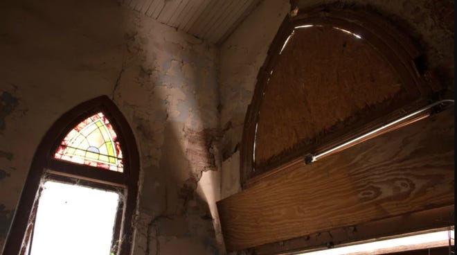 Windows are boarded up inside a church.