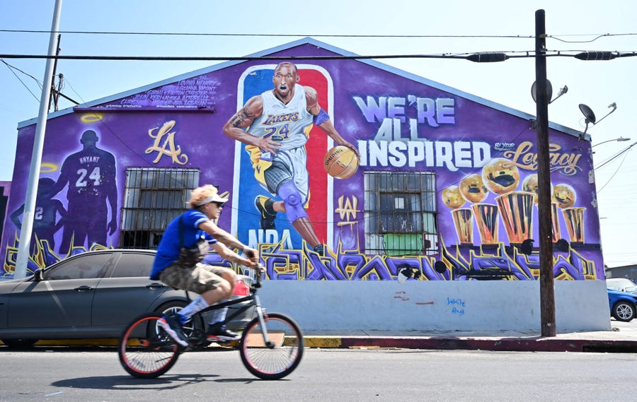 A cyclist rides past "We're All Inspired", a Kobe Bryant mural by artists Hector Arias (aka Tetris Wai) and Plek One on the birthday of the late NBA star of the Los Angeles Lakers on August 23, 2022.