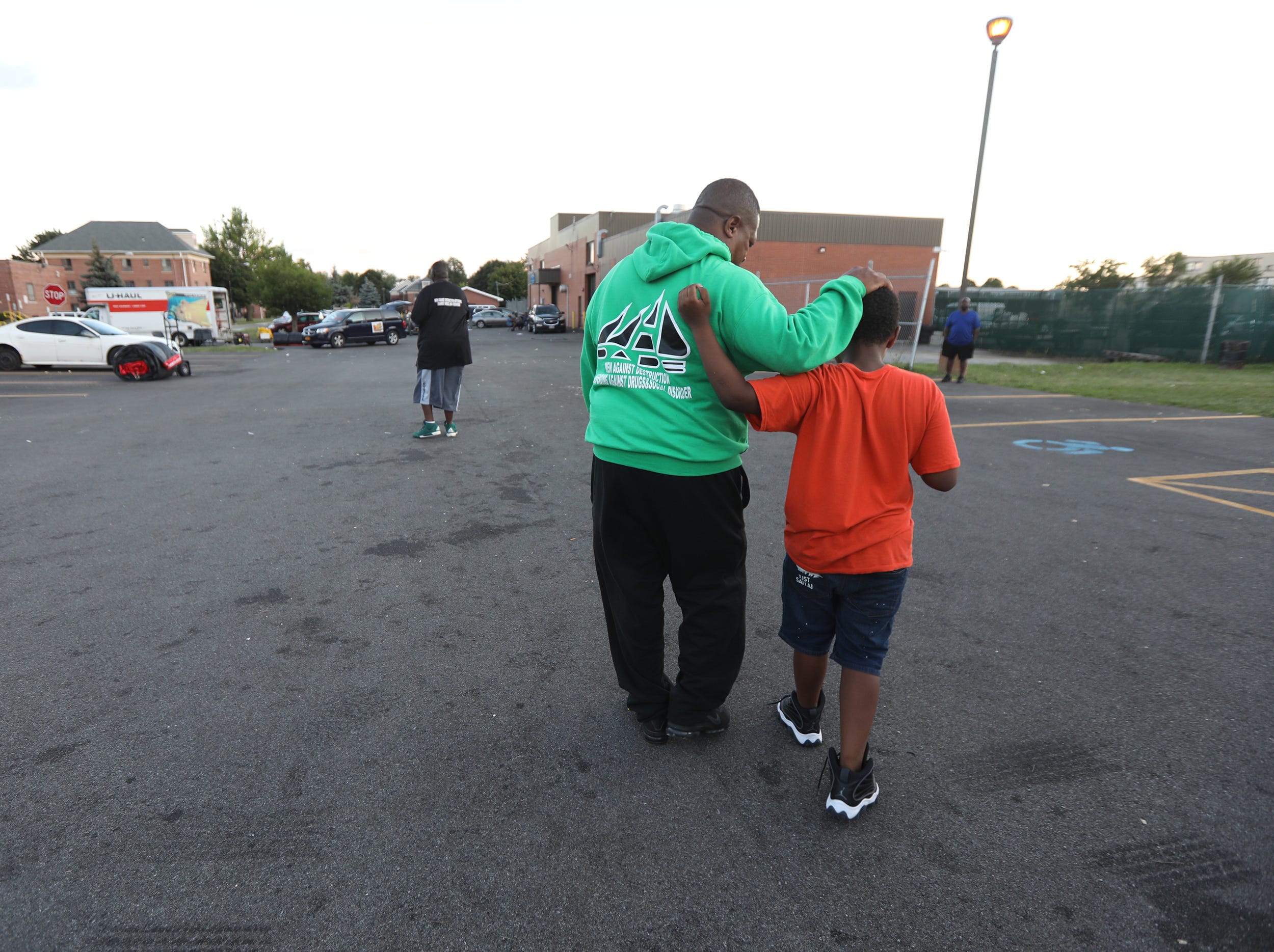 Pastor Kenneth Simmons, president of MAD DADS, walks with his younger cousin, Ricardo Gonzalez, as Gonzalez walks him part way out of the parking lot where Kenfield Homes held their National Night Out on Tuesday, August 2, 2022. The housing project is located on Hempstead Street., in Buffalo, N.Y. Neighbors got to enjoy grilled corn, hamburgers, hot dogs, popcorn, and bounce houses. MAD DADS and Peacemakers hung out making sure it remained a peaceful event.