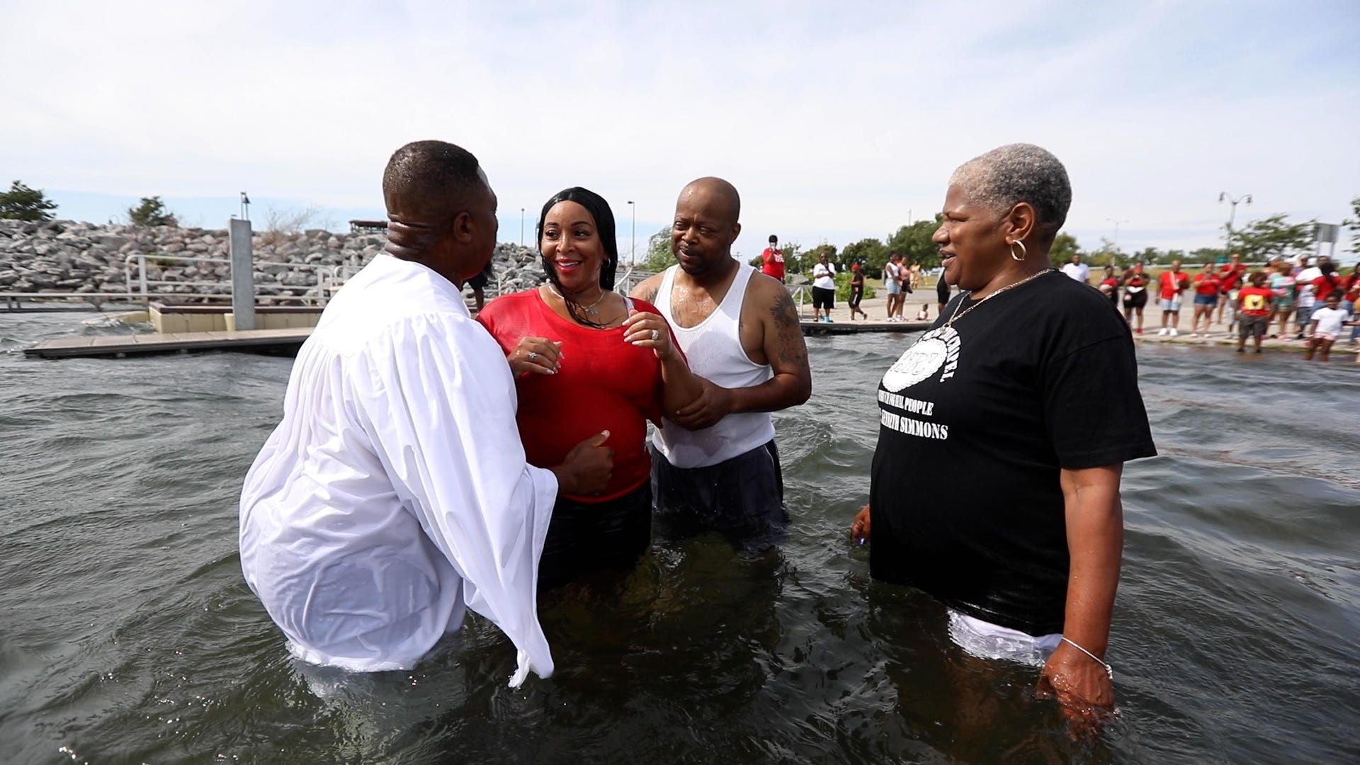 Jamelle Williams-Simmons smiles at her husband, Pastor Kenneth Simmons, after kissing him after her baptism in Lake Erie at Buffalo Harbor State Park on Saturday, July 23, 2022.  She said she felt that this was the right time and suddenly decided to get baptized along with other members of Cold Spring Bible Chapel, who had planned to do it.  Helping with the baptism is Guy Capps.  Watching is Williams-Simmons friend, Lisa Coons, who also got baptized.  Cold Spring Bible Chapel held their annual family picnic that ended with members and anyone else who felt the calling to get baptized.  Simmons and Williams-Simmons were married a few months ago.