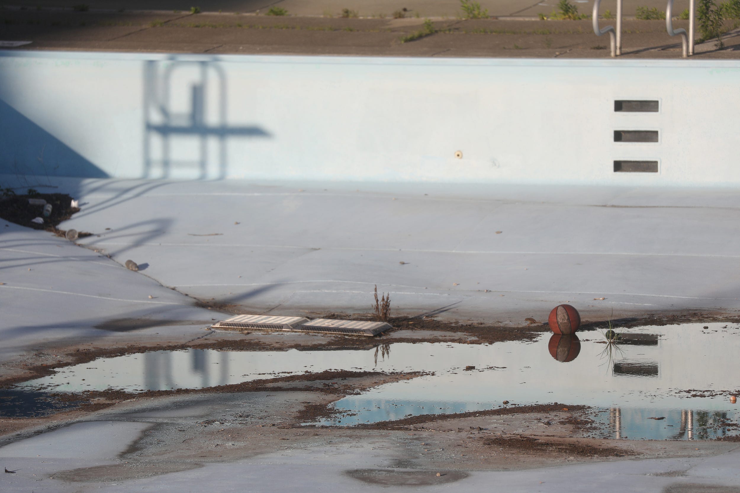 A basketball sits at the bottom of an empty pool in Masten Park in Buffalo, NY on July 26, 2022.  Nine outdoor pools were closed this year due to lack of lifeguards.