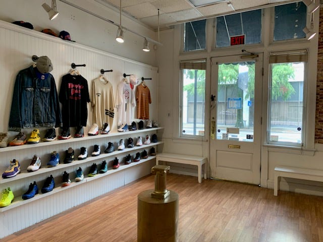 Shelves of shoes and racks of shirts line a wall at The Shoe Gods on Eighth Street, which is now operating with a companion business called Heavyweight Apparel.