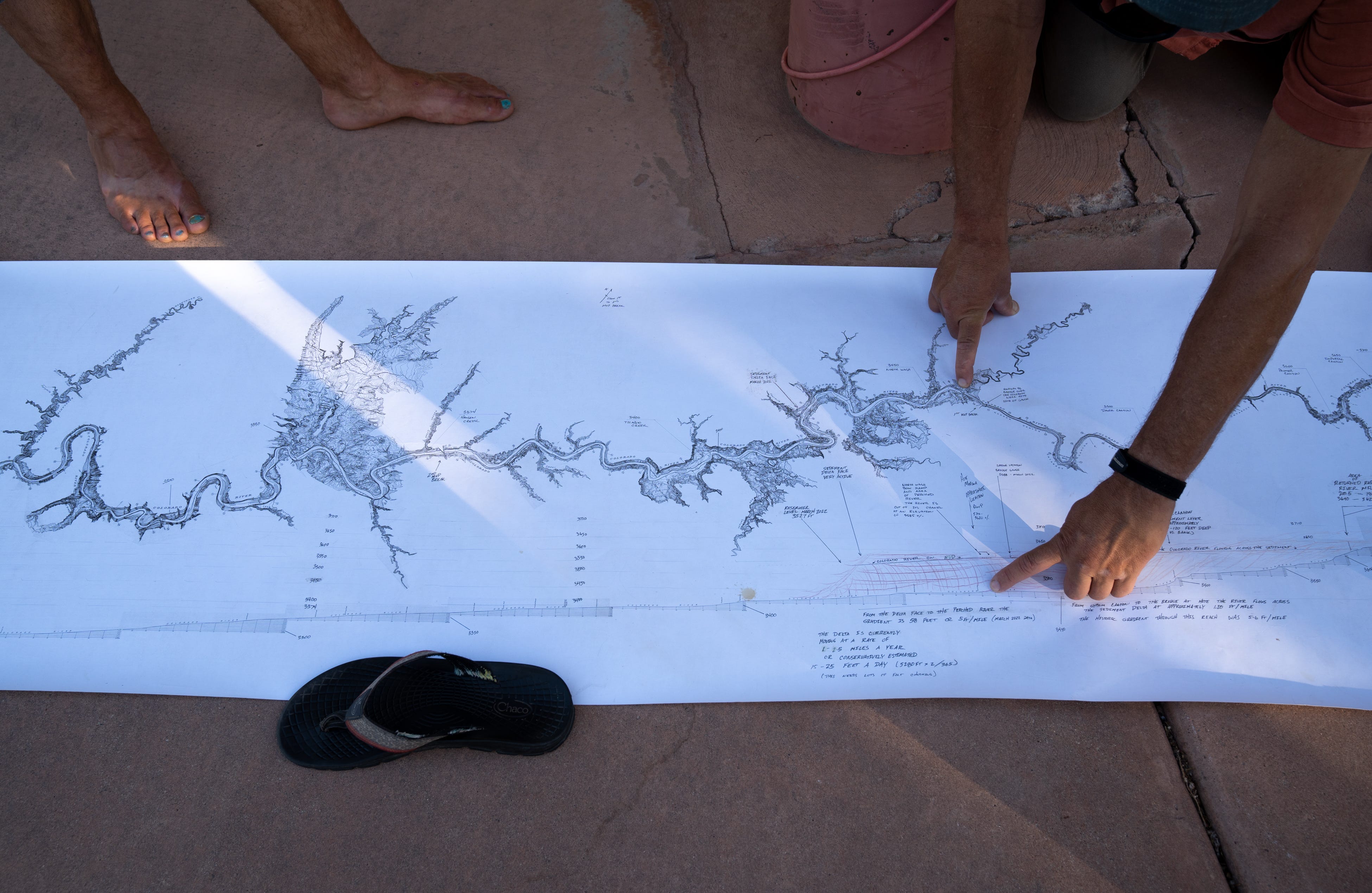 Mike DeHoff (right), with the Returning Rapids Project, points out the sediment delta on a map of the Colorado River at Swanny City Park in Moab, Utah, on June 10, 2022,