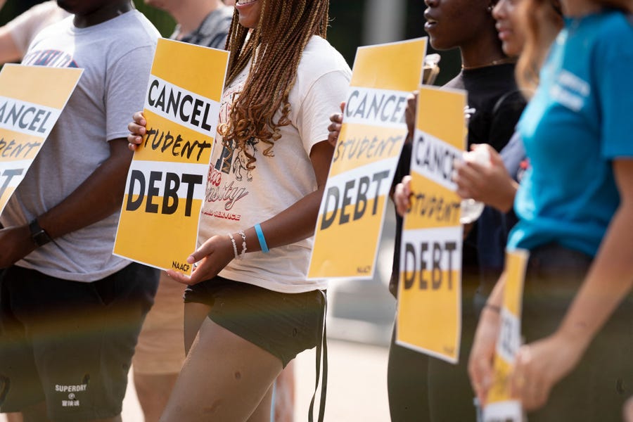 Activists hold cancel student debt signs as they gather to rally in front of the White House in Washington, DC, on August 25, 2022.