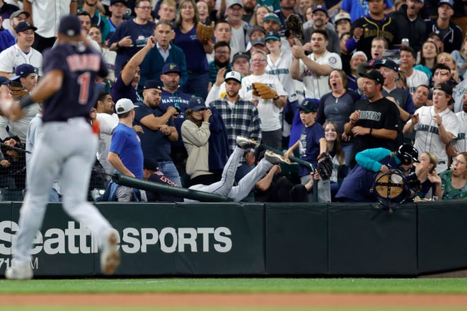 Cleveland Guardians left fielder Steven Kwan dives into the stands to catch a ball hit by Seattle Mariners' Cal Raleigh during the fifth inning of a baseball game, Friday, Aug. 26, 2022, in Seattle. (AP Photo/John Froschauer)