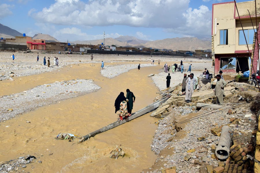 People stand in their partial damage homes caused by flooding after heavy rains on the outskirts of Quetta, Pakistan, Saturday, Aug. 27, 2022. Officials say flash floods triggered by heavy monsoon rains across much of Pakistan have killed nearly 1,000 people and displaced thousands more since mid-June.
