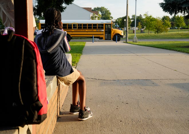 Faith Harris, 11, watches a school bus as she waits in front of Windsor STEM Academy in Linden for the first day of districtwide in-person classes to begin Aug. 29 for Columbus City Schools.