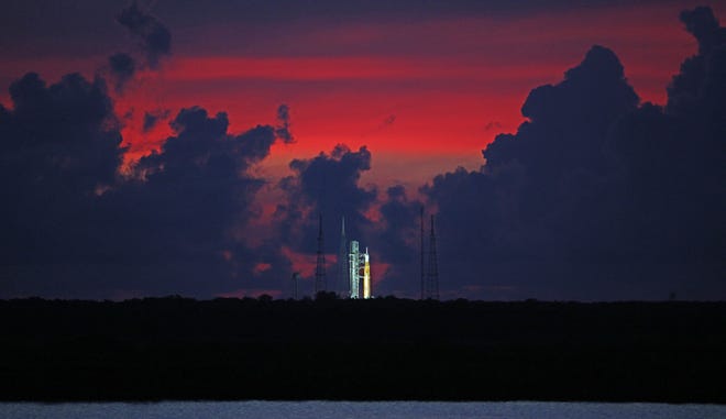The sky begins to clear before dawn, highlighting the Artemis-1 moon rocket at Launch Pad 39 at the Kennedy Space Center, in this view from Titusville, Florida on Aug. 23, 2022.