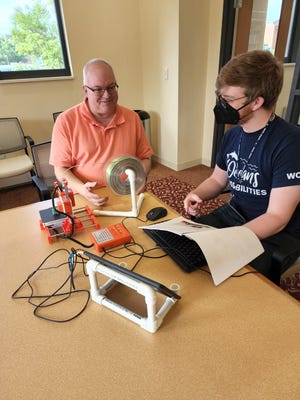 Wayne County Library patrons work on a 3D printer. The service of the printer is available through the library to patrons.