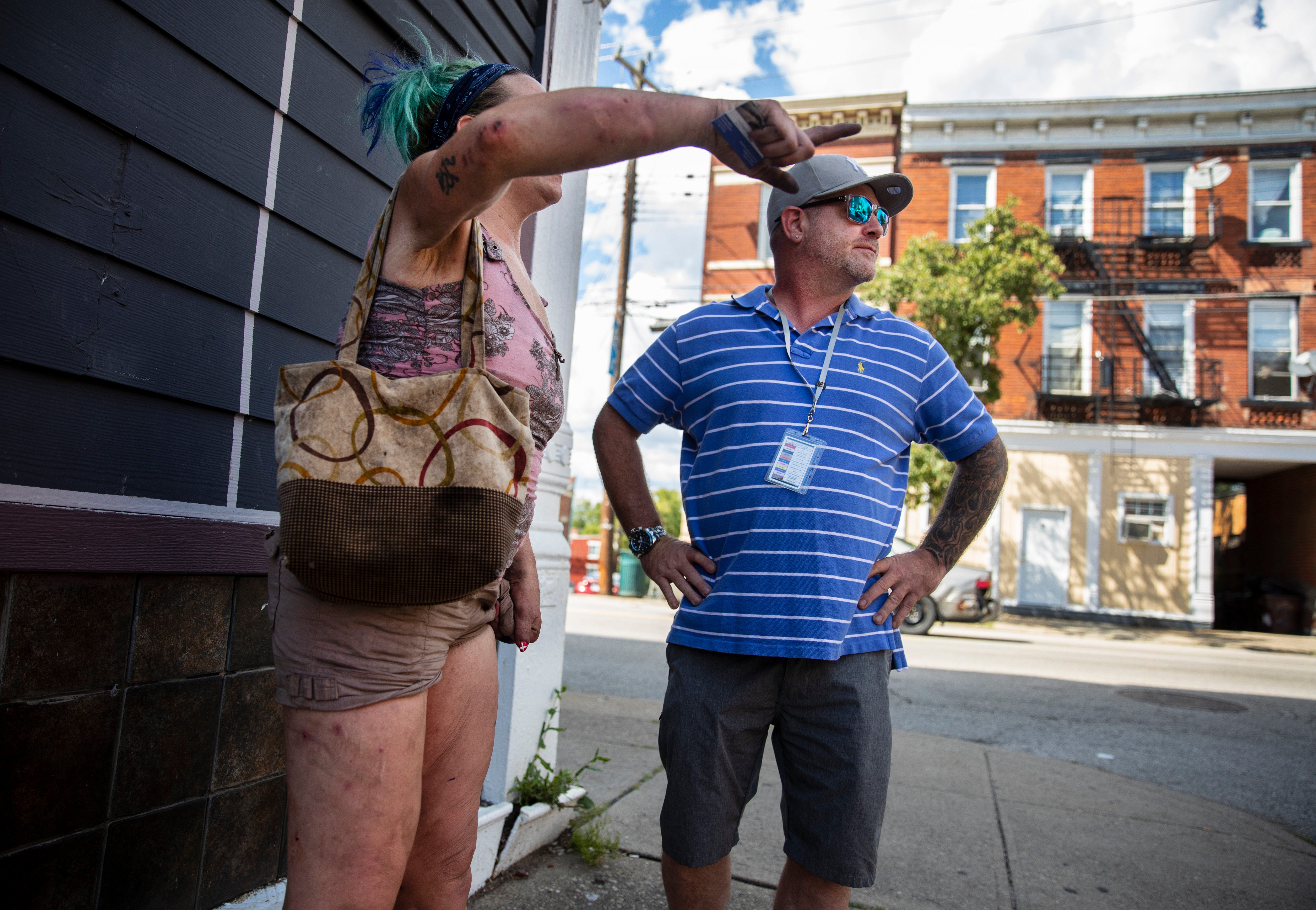 Outreach worker Tony Wilson talks to a woman on Warsaw Street. He gave her a card with resource numbers on it, in case she wanted to reach out to him later for help.