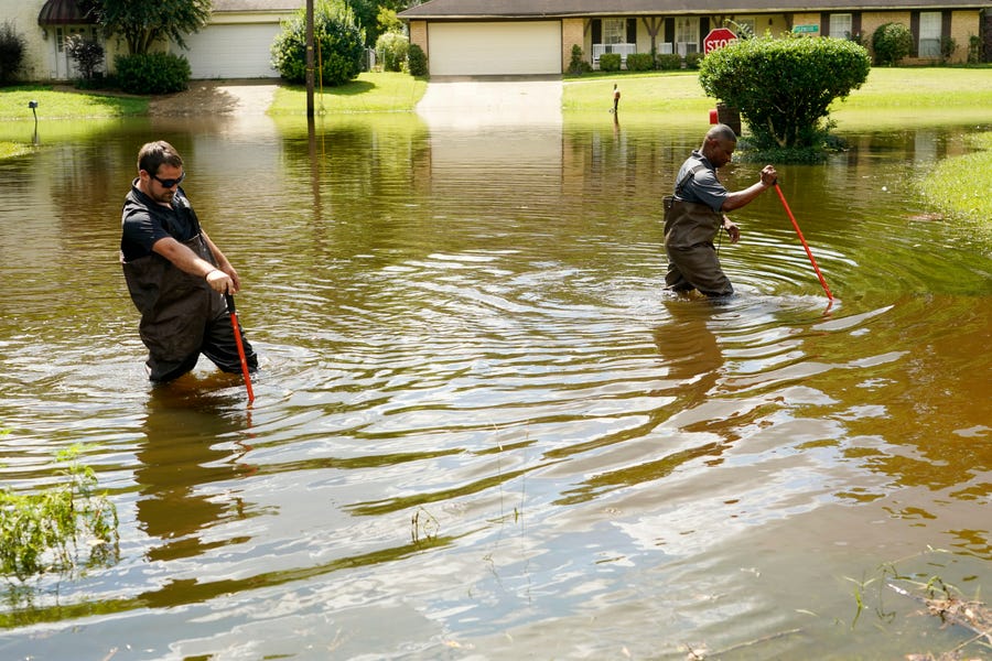 Hinds County Emergency Management Operations deputy director Tracy Funches, right, and operations coordinator Luke Chennault, wade through flood waters in northeast Jackson, Miss., Monday, Aug. 29, 2022, as they check water levels. Flooding affected a number neighborhoods that are near the Pearl River.