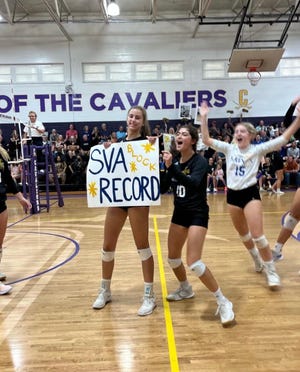 Mattie Lynch, holding sign, celebrates with teammates after setting school career record for blocks Tuesday.