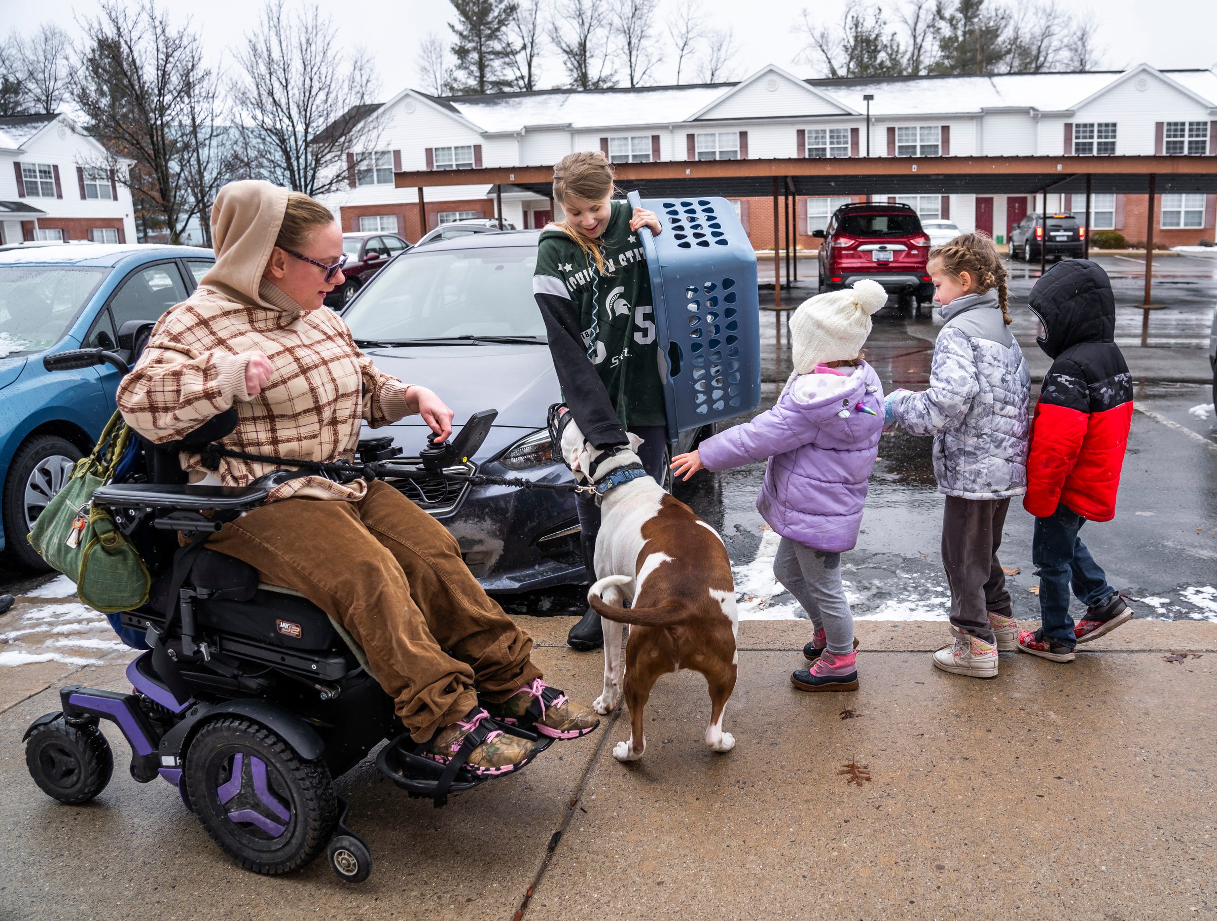 Cody Masson, 33, of Traverse City, takes her dog, Pluto, for a walk as children pet him outside her apartment complex on Thursday, March 31, 2022.