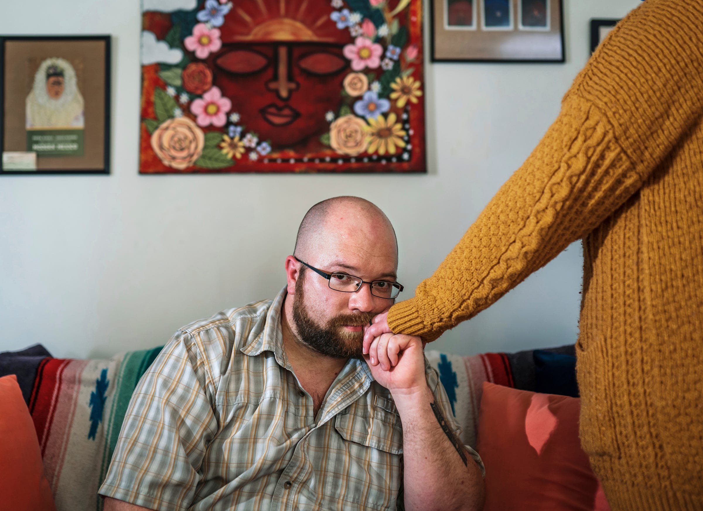 Christopher Land, of Taylor, holds the hand of his wife, Jennifer, at their home on Wednesday, March 30, 2022. The Lands say they don't understand why Jennifer did not qualify for recipient rights protection under the mental health code when she was in a hospital emergency room.