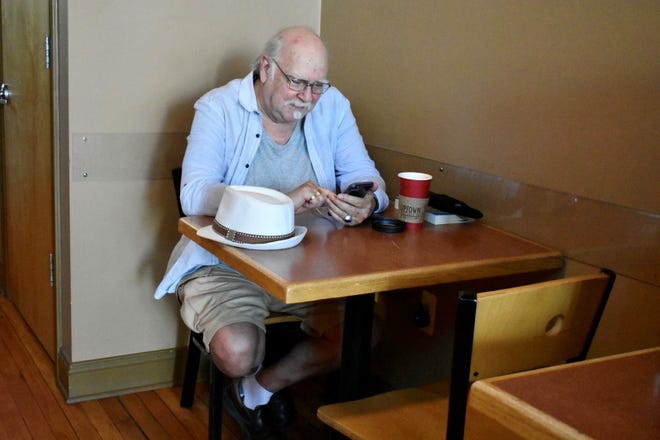 Michael Johnson se sienta en Uptown Coffeehouse en Howell el 31 de agosto de 2022 para cargar su teléfono después de que la tormenta del lunes causara cortes de energía en todo el condado.
