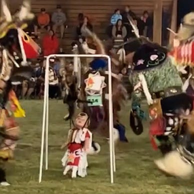 Baby jumps around as elders dance during First Nations powwow