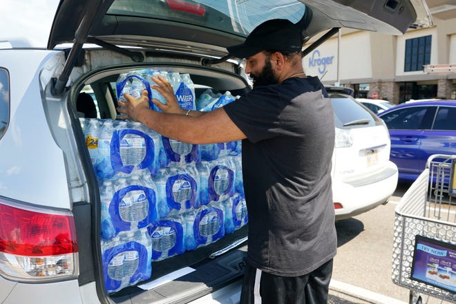 Rajwinder Singh, a gas station/convenience store owner, pats into place 15 cases of drinking water he purchased from a Kroger grocery store into his vehicle in Jackson, Mississippi. Parts of Jackson were without running water Tuesday because recent flooding worsened problems in one of two water-treatment plants as part of the city's response to longstanding water system problems.