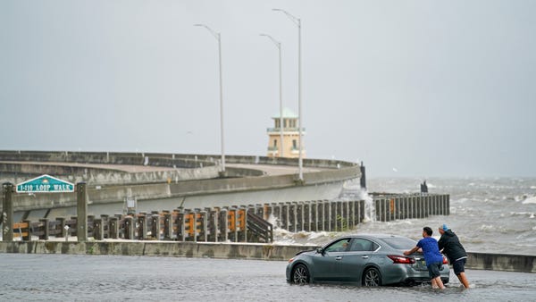 Two men help a stranded motorist in floodwaters on
