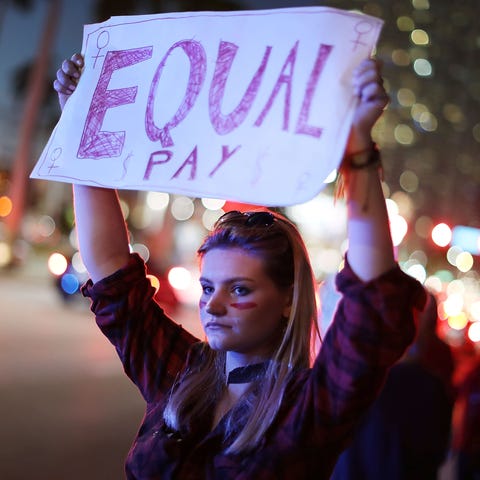 Clarissa Horsfall holds a sign reading, "Equal Pay