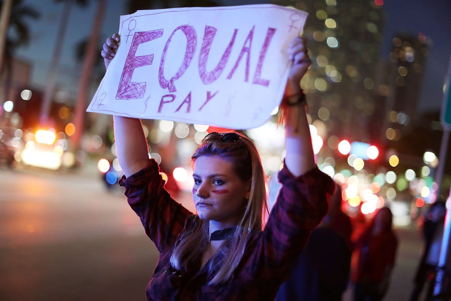 Clarissa Horsfall holds a sign reading, "Equal Pay," as she joins with others during 'A Day Without A Woman' demonstration in Miami on March 8, 2017.