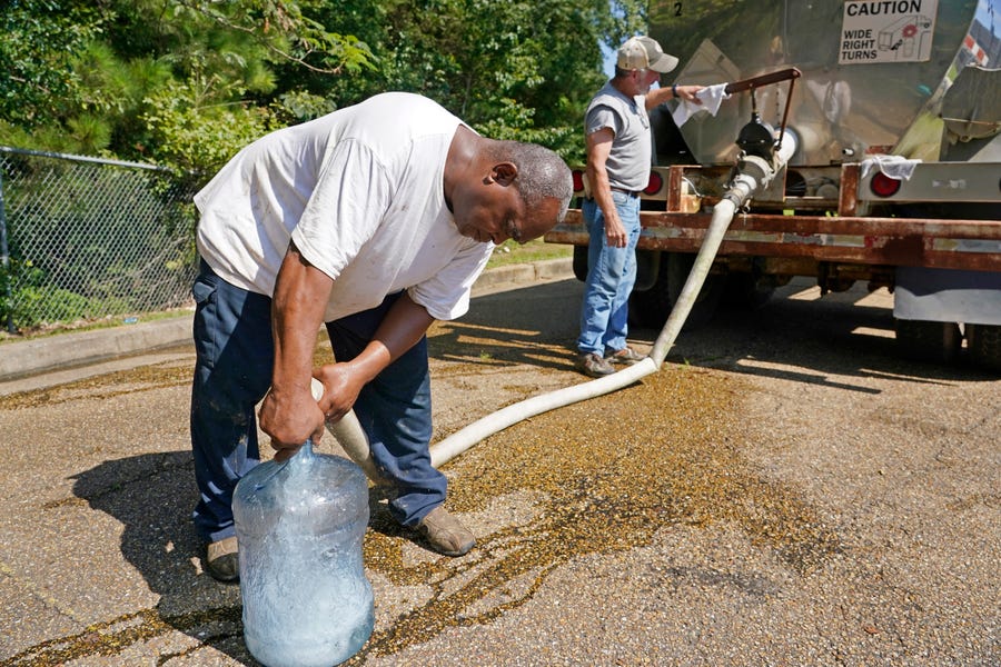 Ty Carter, right, and Benjamin Williams, with Garrett Enterprises, fill up a five-gallon jug from a water tanker that is one of two placed in Jackson, Miss., to provide residents with non-potable water. The recent flood worsened Jackson's longstanding water system problems and the state Health Department has had Mississippi's capital city under a boil-water notice since late July.
