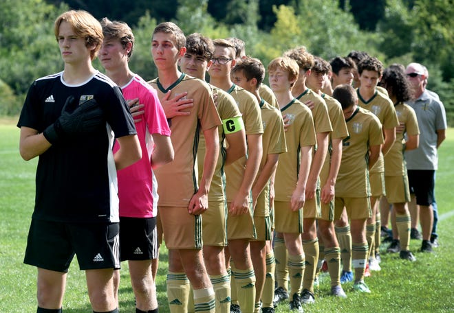 St. Mary Catholic Central goalkeeper Trent Zachel (front) stands with his teammates as the national anthem is played before their soccer contest against Flat Rock Wednesday. Zachel moved out of goal in the second half and scored the first two goals of his career to lead the Falcons to an 8-0 win.