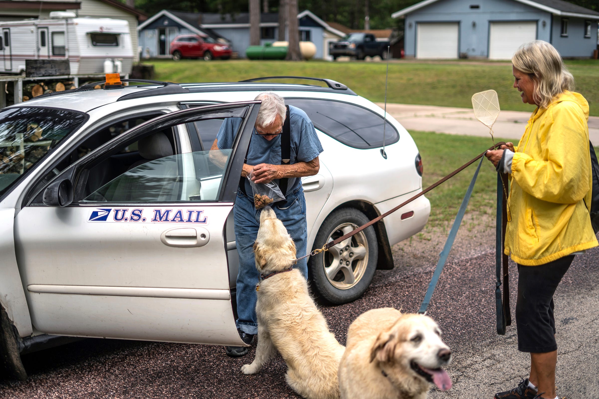 Mailman Ron Curtis, 86, of Wetmore stops to talk with Cindy Disher of Atlanta and give treats to her two dogs Belle and Ames as she walks along the street in Michigan's Upper Peninsula on Wednesday, July 27, 2022.